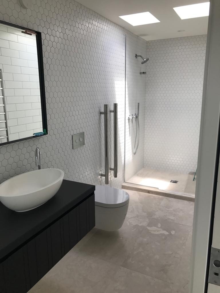 Finished bathroom with a curved hexagon mosaic wall, fitted and styled