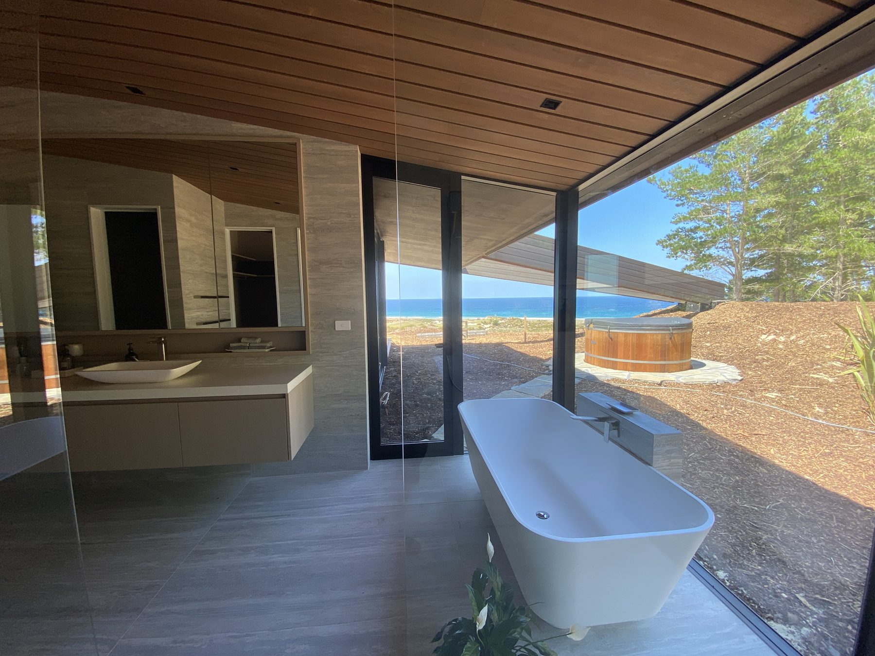 Coastal ensuite bathroom with ocean view, large format tiles and freestanding bath — Bespoke Tiling Solutions