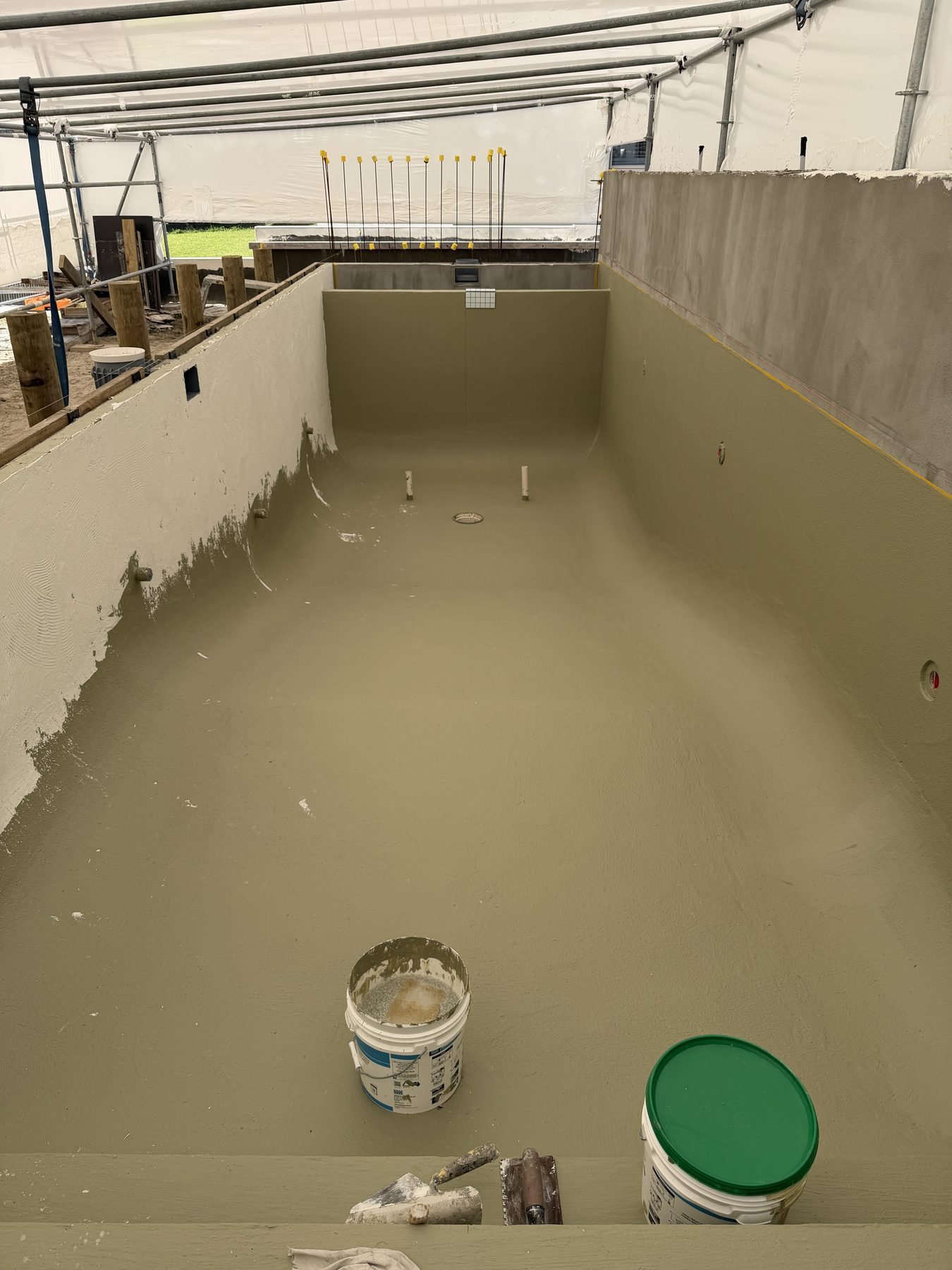 Immersion-rated waterproofing membrane part-applied across a swimming pool shell